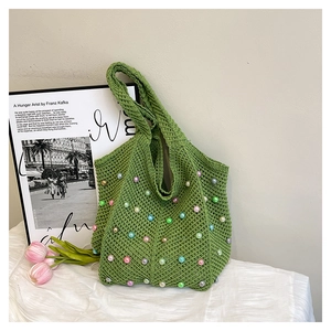 Detail of green crochet woven tote bag featuring colorful pearl beads and soft texture
