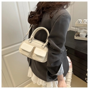 Creamy white bowling style handbag with dual front pockets and silver metal hardware detail