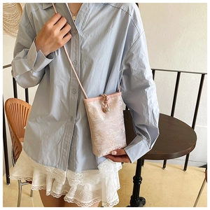 Détail de la broderie jacquard sur un petit sac bandoulière vertical pour téléphone