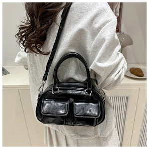 Detail of black glossy pillow bag with double front pockets and silver hardware