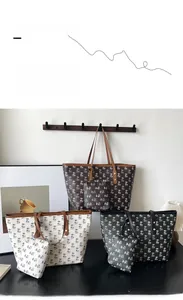 Close-up of three palm-printed tote bags in coffee, cream, and black colors with gold hardware