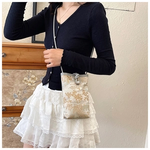 Close-up of vintage style crossbody phone bag with golden jacquard mountain patterns