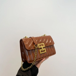 Close-up of a redwood quilted crossbody bag with gold metallic buckle and chain strap