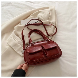 Close-up of shiny burgundy leather pillow bag with double front pockets and shoulder strap
