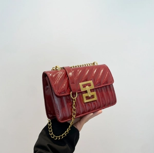 Macro detail of red quilted patent leather shoulder bag with gold metal twist lock