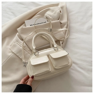 Close-up of a cream multi-pocket faux leather crossbody bag with silver hardware on a blazer