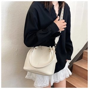 Close-up of cream bucket bag with lychee texture and ethnic embroidered wide strap