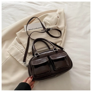 Detail shot of a dark brown vintage pillow bag on a beige jacket and prop book
