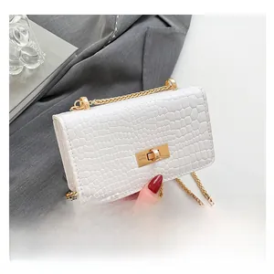 Detail of white crocodile pattern shoulder bag with golden chain and metallic twist lock