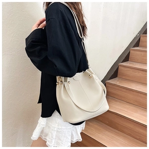 Close-up of beige lychee grain leather bucket bag with decorative gold spherical hardware