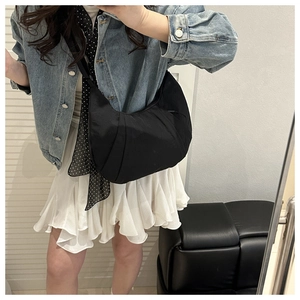 Mirror selfie showing the black pleated nylon crescent crossbody bag worn by a model