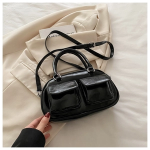 Detail of glossy black patent leather bag with utility pockets and silver metal hardware