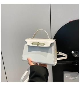Detailed view of cream leather tote with golden twist lock and elegant handle