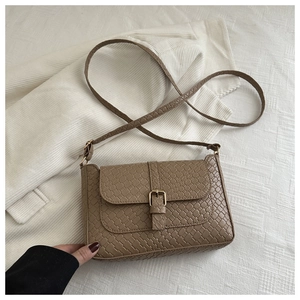 Close-up of woven texture crossbody bag with gold buckle on white striped blazer