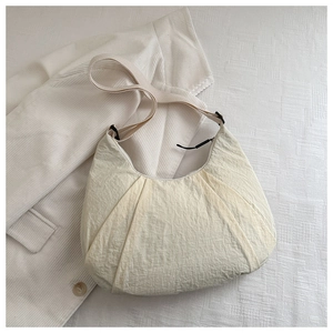 Detailed close-up of ivory crescent bag featuring pleated texture and nylon fabric finish