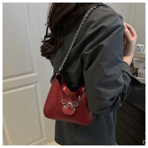 Close-up of red matte leather shoulder bag with silver bow and chunky chain strap