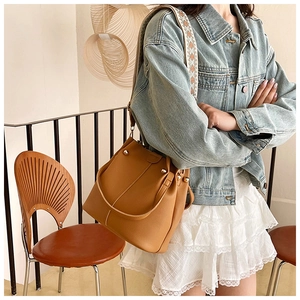 Detail of camel bucket bag with lychee texture leather and ethnic embroidered strap