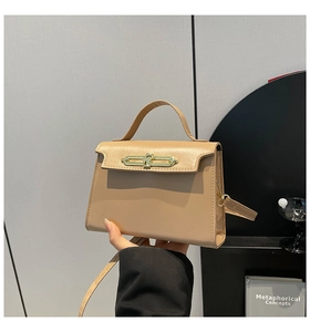 Close-up of khaki leather handbag featuring a unique gold metal chain-link lock detail