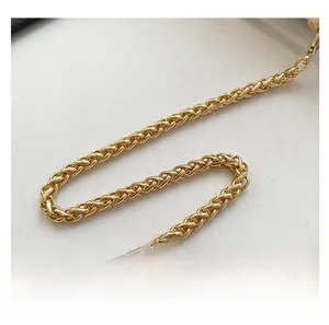 Close-up of golden woven metal chain strap with secure hooks for crossbody square bags