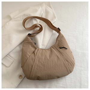 Detail view of khaki nylon dumpling bag with pleated texture and adjustable strap