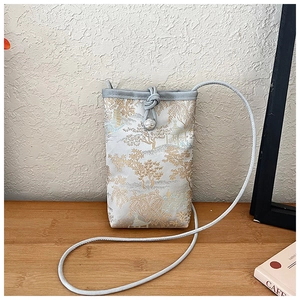 Détail de broderie de paysage sur pochette de téléphone en brocart avec fermoir fleur