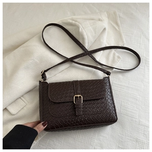 Detail of dark brown woven texture handbag with golden buckle and sleek leather strap