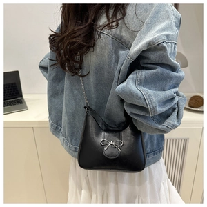 Close-up of a black crescent shoulder bag with silver bow detail and metal chain strap