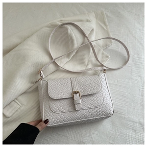 Detail of white woven texture shoulder bag with gold square buckle and flip cover
