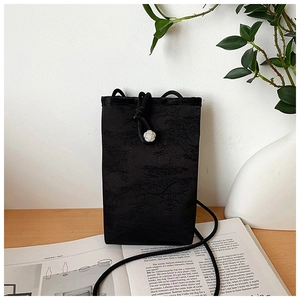 Détail du sac à téléphone brodé en jacquard noir avec cordon et bouton rose blanche
