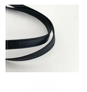 Detailed close-up of smooth leather handle with clean stitching on a black tote bag