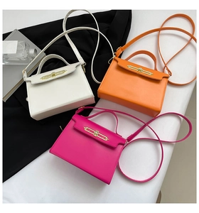 Three elegant leather handbags in white, orange, and pink with gold metal bar clasps