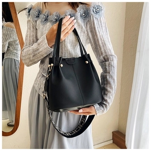 Detail of black leather bucket bag featuring gold studs and geometric jacquard strap