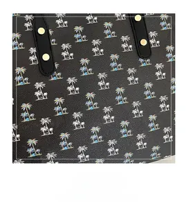 Detail of black tote bag featuring colorful palm tree prints and golden metal studs