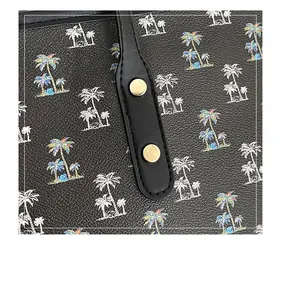 Close-up of printed tote bag featuring gold hardware reinforcement and palm tree patterns