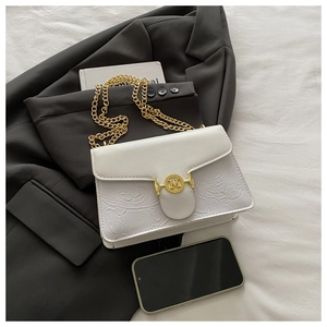 Close-up of white embossed square bag with golden M buckle and chain on grey blazer