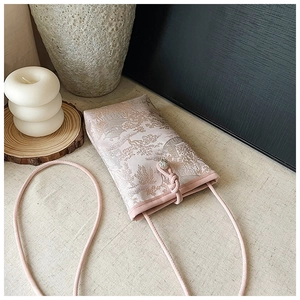 Détail d'un sac téléphone rose avec broderie orientale et bandoulière en cordon élégante