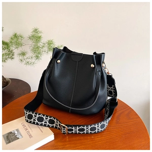 Detail view of black pebble leather bucket bag with geometric patterned wide strap