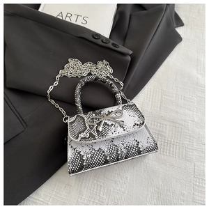 Detail of crocodile pattern small square bag with silver bow buckle and chain strap