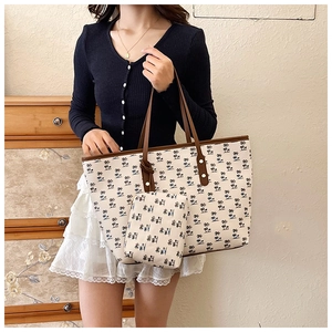 Detail of printed canvas tote bag set with palm tree patterns and brown leather handles