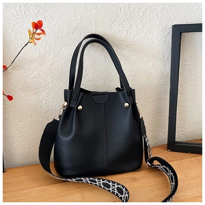 Detail of black lychee grain leather bucket bag with geometric wide strap and gold hardware