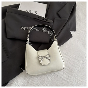 Detailed close-up of white bow-knot hobo bag with silver chain on minimalist background