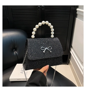 Detail of glitter handbag featuring faux pearl handle and silver bow hardware