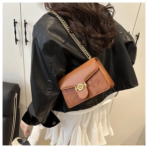 Détail du sac bandoulière marron avec chaîne dorée et motifs de lotus gaufrés