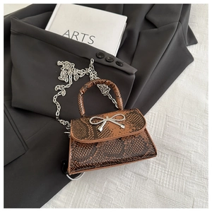 Detail view of brown crocodile texture mini bag with silver bow accent and chain strap