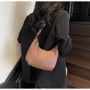 Detail of caramel brown matte leather hobo bag with vertical stitching and gold hardware