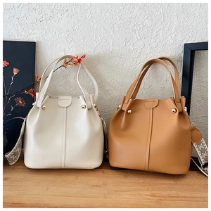 Detailed close-up of textured faux leather bucket bag with decorative ethnic strap