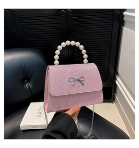 Detailed view of pink glitter handbag featuring pearl handle and silver bow buckle detail