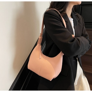 Detailed view of pink soft leather shoulder bag worn by model on a minimalist staircase