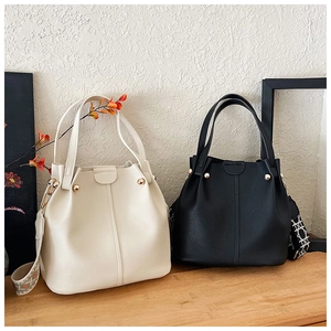 Detail of minimalist bucket bags in beige and black leather with retro jacquard straps