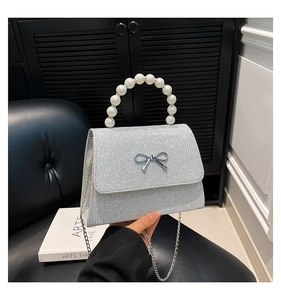 Close-up of silver glitter crossbody bag featuring a pearl handle and metal bow detail